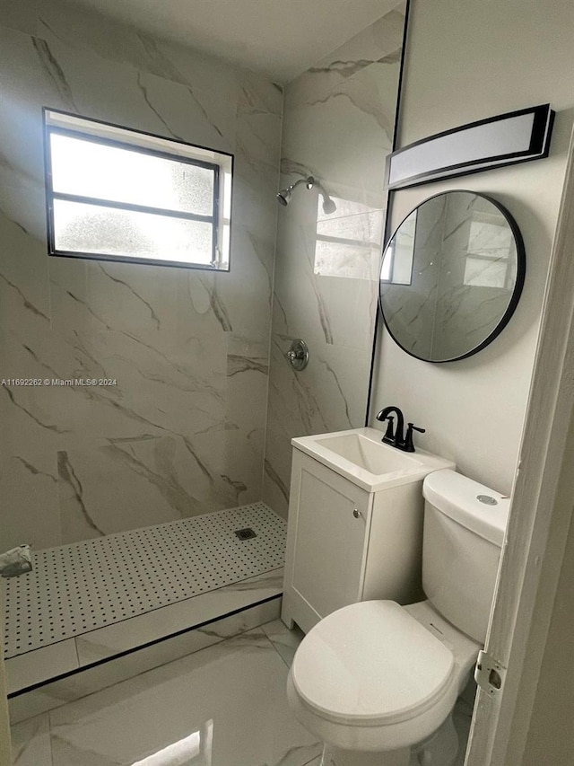 bathroom with toilet, vanity, and tiled shower