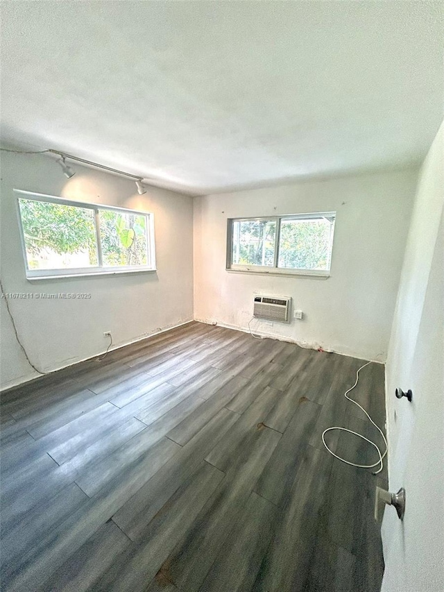 unfurnished room with a textured ceiling, a wall mounted air conditioner, and wood finished floors