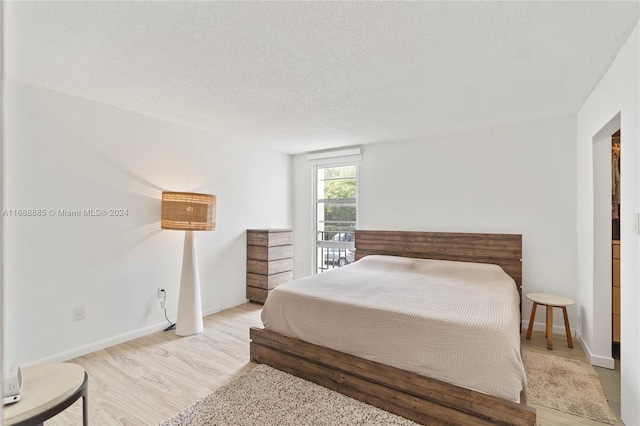 bedroom featuring light hardwood / wood-style floors and a textured ceiling