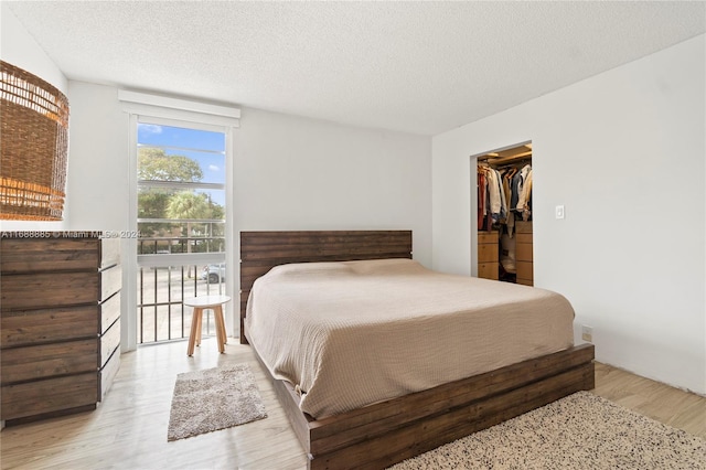 bedroom featuring wood-type flooring, a textured ceiling, a spacious closet, and a closet