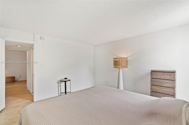 bedroom with a textured ceiling and light hardwood / wood-style flooring