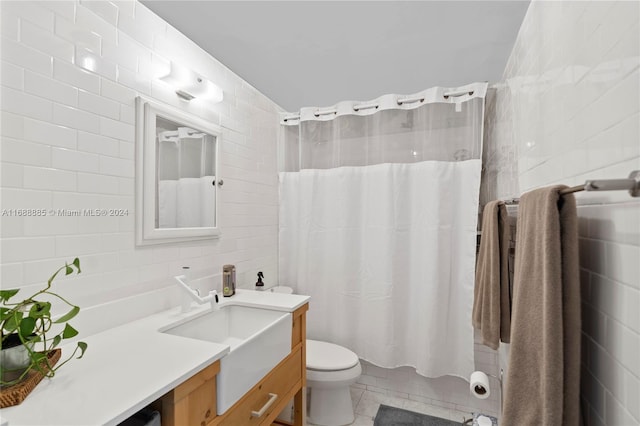 bathroom with tile patterned floors, vanity, tile walls, and toilet