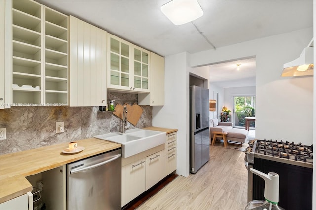 kitchen featuring tasteful backsplash, stainless steel appliances, exhaust hood, sink, and light hardwood / wood-style flooring