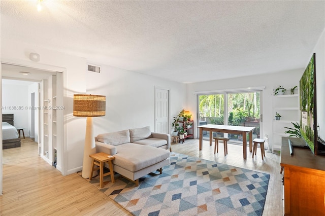 living room with light hardwood / wood-style floors and a textured ceiling