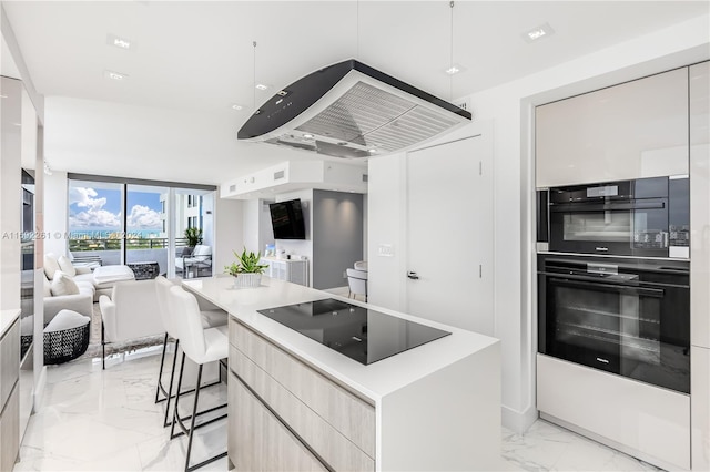 kitchen with a kitchen breakfast bar, exhaust hood, black appliances, and a center island