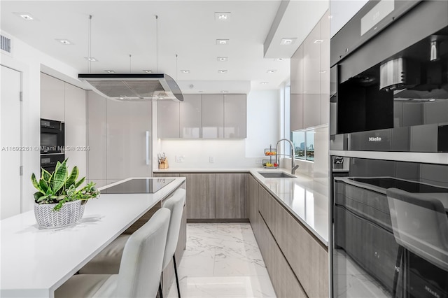 kitchen with black appliances, a breakfast bar, sink, and range hood