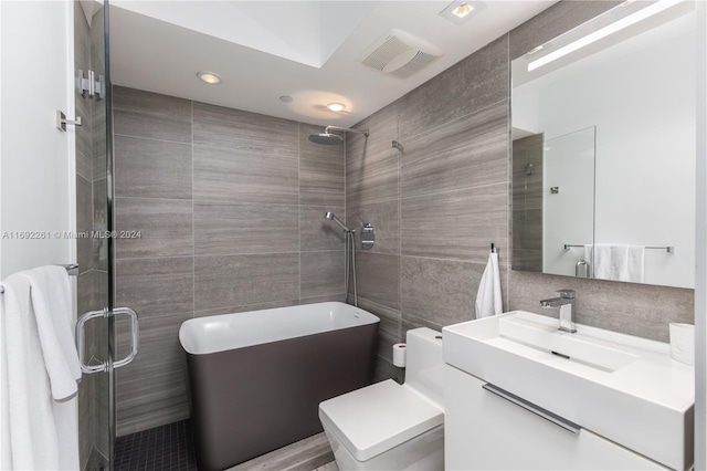 bathroom featuring toilet, vanity, tile walls, and a shower with shower door