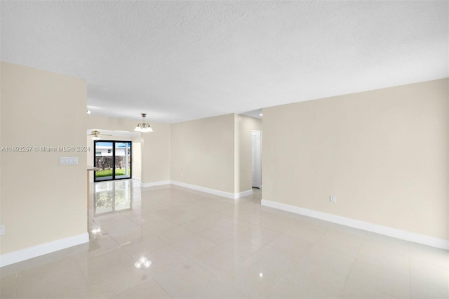 unfurnished room featuring an inviting chandelier, light tile patterned floors, and a textured ceiling