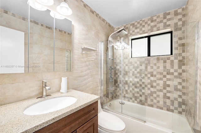 full bathroom featuring tile walls, vanity, combined bath / shower with glass door, and toilet