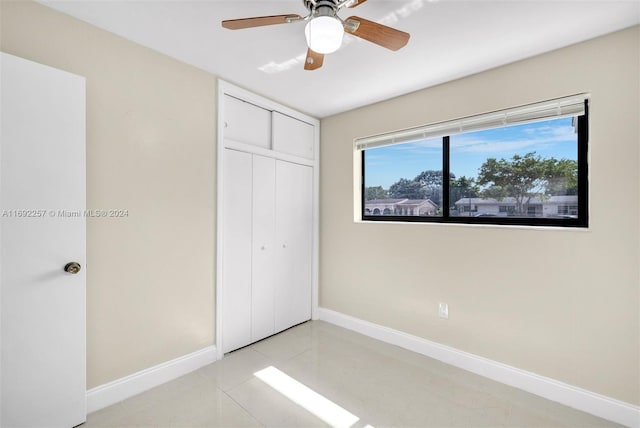 unfurnished bedroom featuring light tile patterned floors, ceiling fan, and a closet