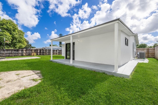 back of property featuring central AC unit, a patio area, and a yard