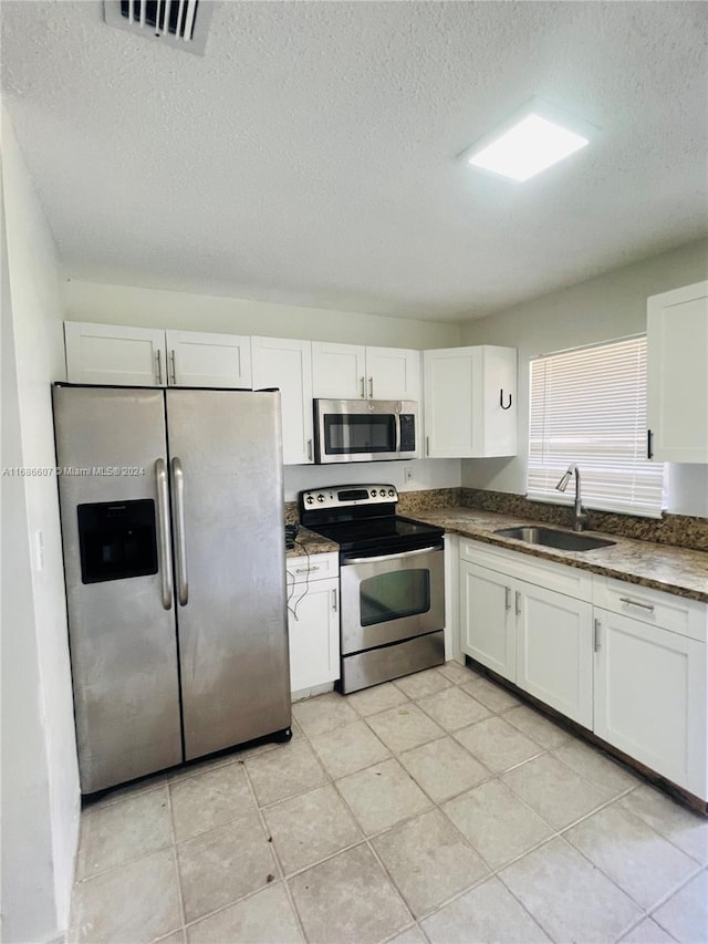 kitchen with a textured ceiling, white cabinets, sink, and stainless steel appliances