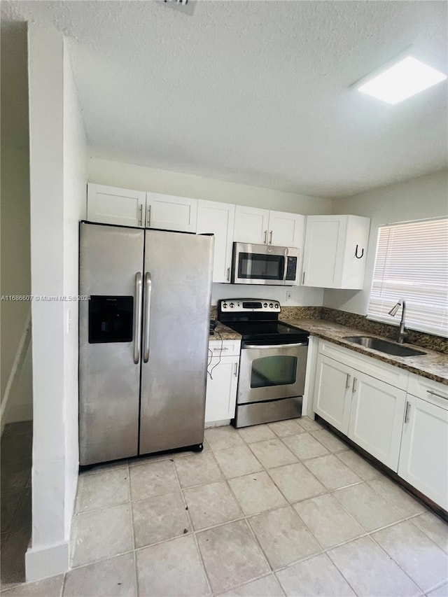 kitchen with white cabinets, appliances with stainless steel finishes, a textured ceiling, and sink