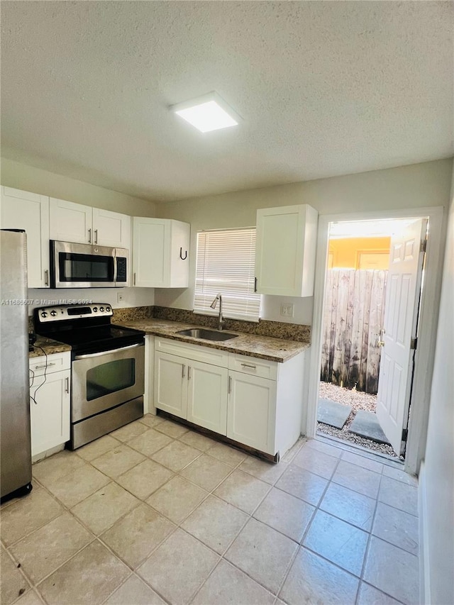 kitchen featuring stainless steel appliances, plenty of natural light, sink, and white cabinets