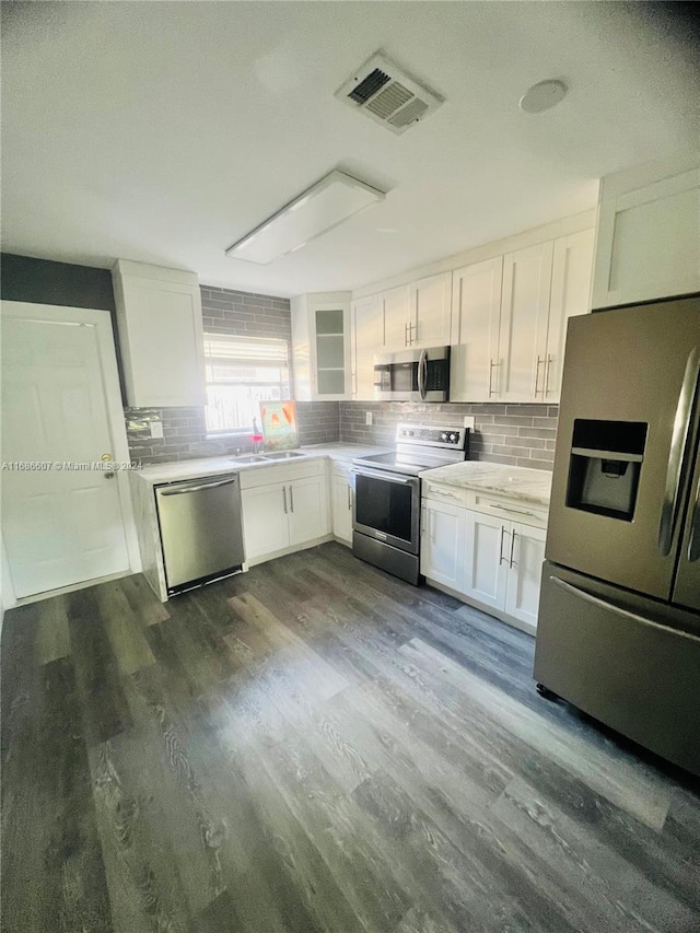 kitchen with stainless steel appliances, white cabinetry, backsplash, dark hardwood / wood-style floors, and sink