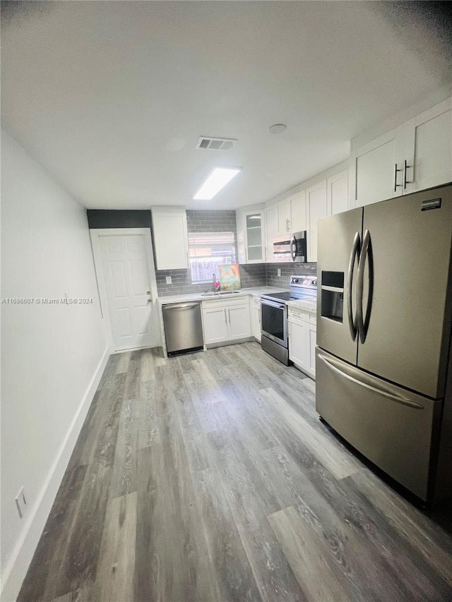 kitchen featuring stainless steel appliances, backsplash, sink, white cabinets, and light hardwood / wood-style flooring