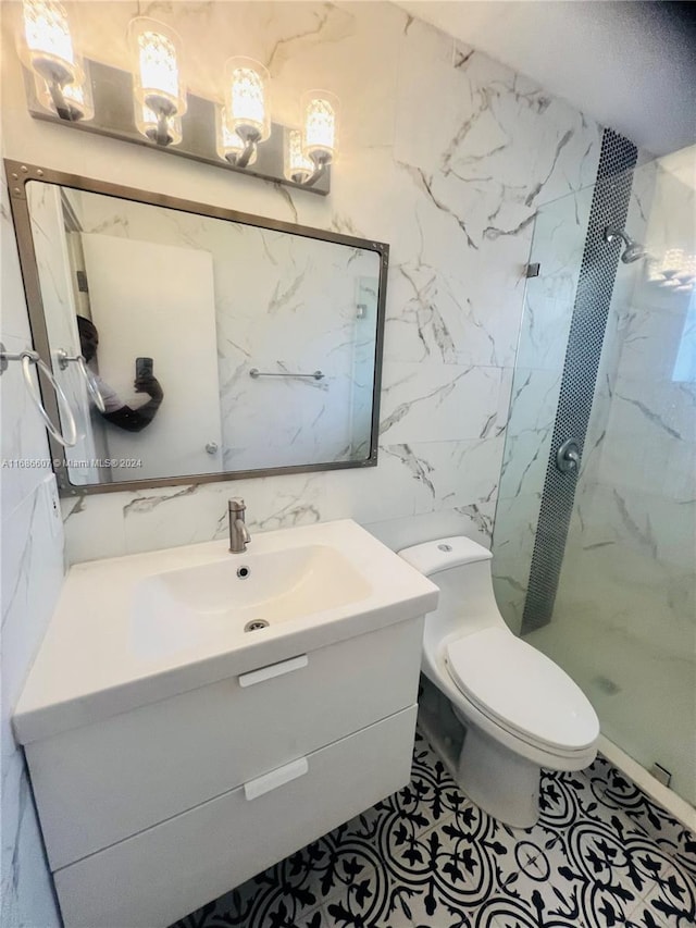 bathroom with tile walls, vanity, toilet, and tiled shower