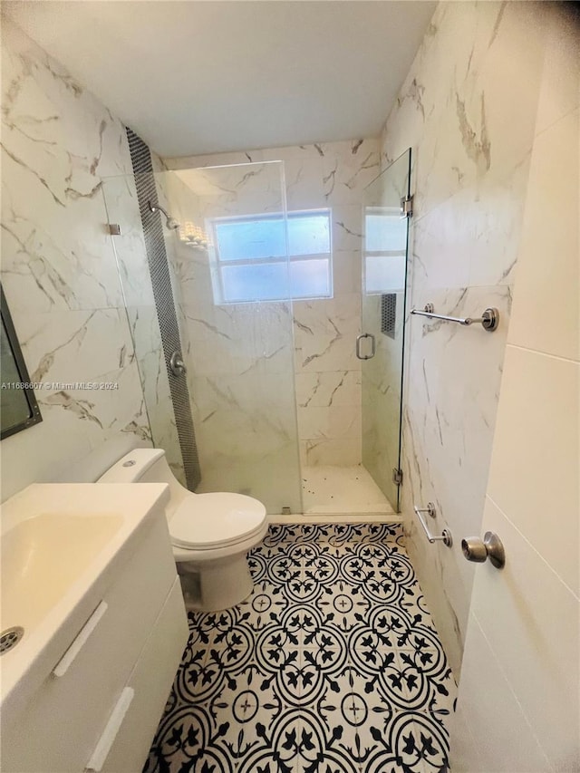 bathroom with tile walls, vanity, toilet, and a shower with shower door