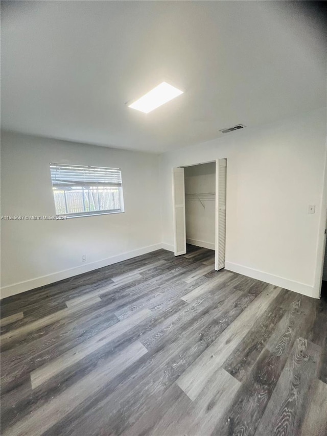 unfurnished bedroom featuring a closet and dark hardwood / wood-style floors