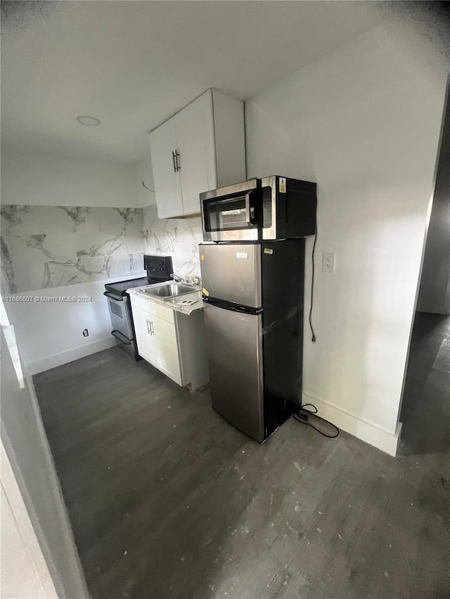 kitchen with stainless steel appliances, sink, white cabinets, dark wood-type flooring, and decorative backsplash