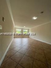 empty room with tile patterned flooring and crown molding