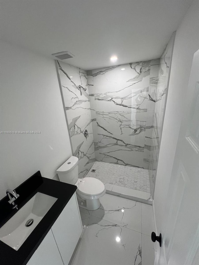 bathroom with toilet, vanity, and tiled shower