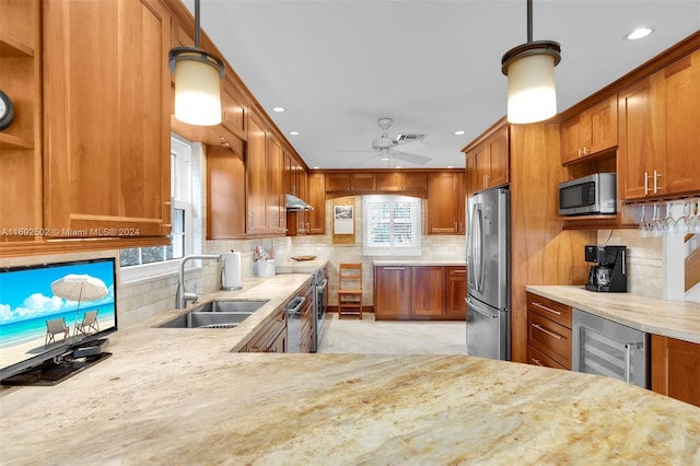 kitchen with decorative light fixtures, beverage cooler, appliances with stainless steel finishes, and sink