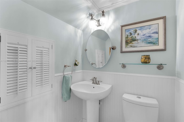 bathroom with toilet, sink, and ornamental molding