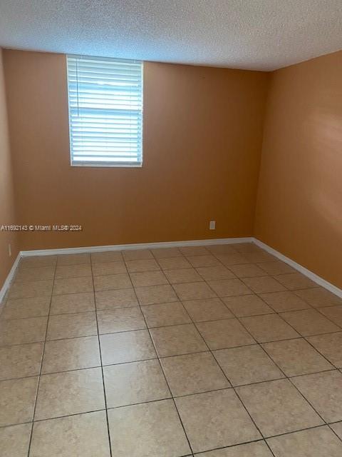 tiled spare room with a textured ceiling