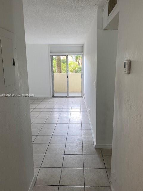 tiled empty room featuring electric panel and a textured ceiling