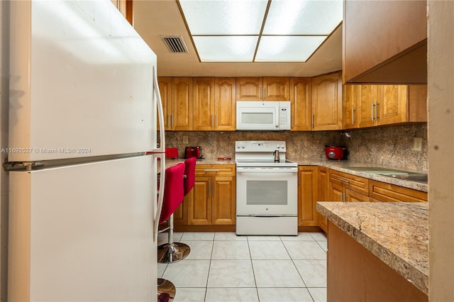 kitchen featuring white appliances, decorative backsplash, and light tile patterned floors