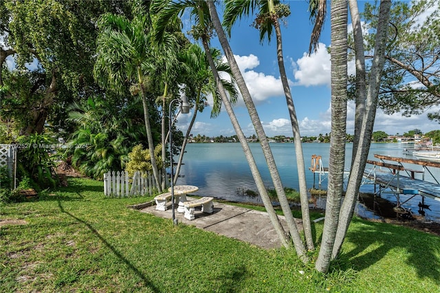 view of dock with a lawn and a water view