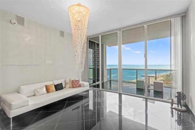 tiled living room featuring floor to ceiling windows, a water view, a beach view, and an inviting chandelier