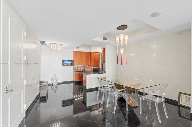 dining area featuring a raised ceiling and dark tile patterned floors