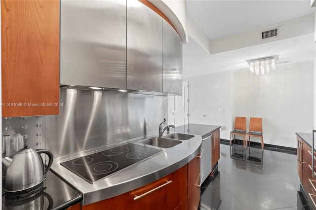 kitchen featuring stainless steel counters, black electric stovetop, dark tile patterned flooring, and sink