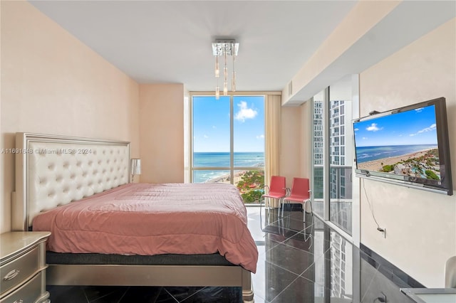 bedroom with dark tile patterned floors and a wall of windows