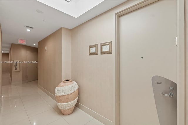 corridor with light tile patterned floors and a skylight