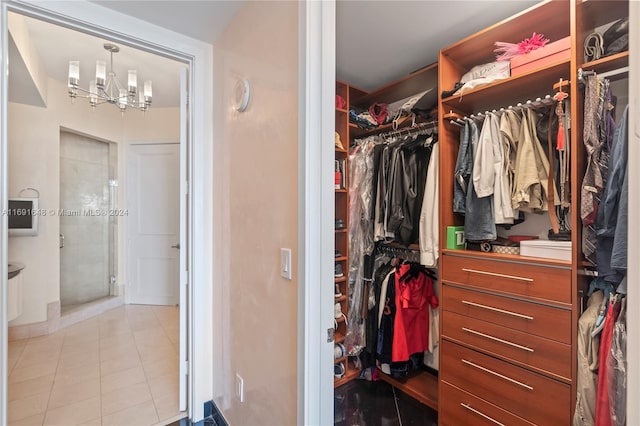 spacious closet featuring light tile patterned floors and an inviting chandelier