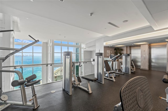 gym featuring elevator and a water view