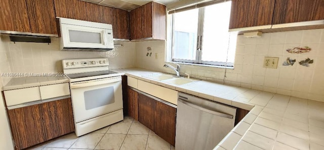 kitchen with light tile patterned flooring, sink, backsplash, tile counters, and white appliances