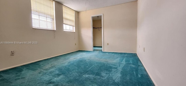 unfurnished bedroom featuring a closet, carpet floors, a textured ceiling, and a spacious closet