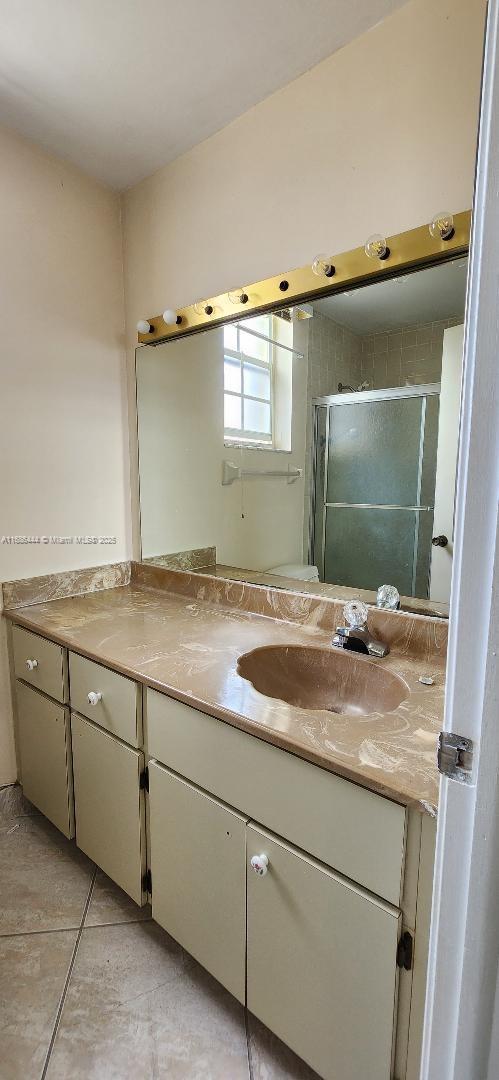 bathroom with tile patterned flooring, vanity, and a shower with shower door