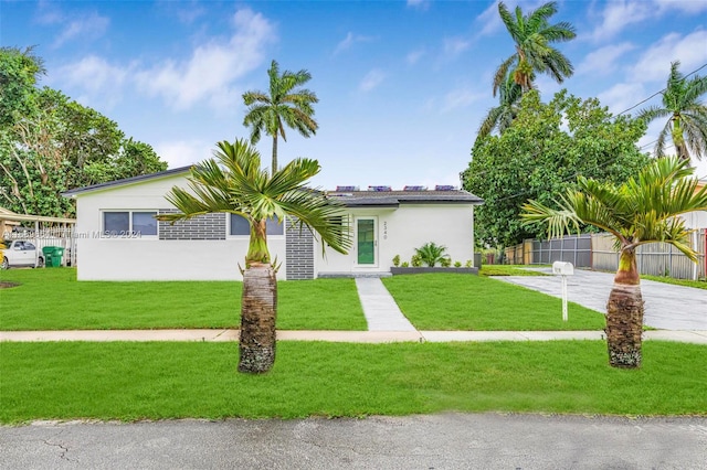 view of front of home featuring solar panels and a front lawn