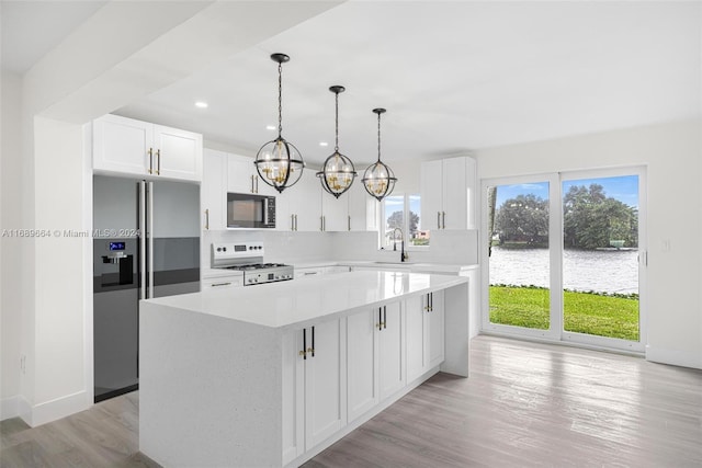 kitchen featuring white cabinetry, high end refrigerator, stove, light hardwood / wood-style floors, and a center island