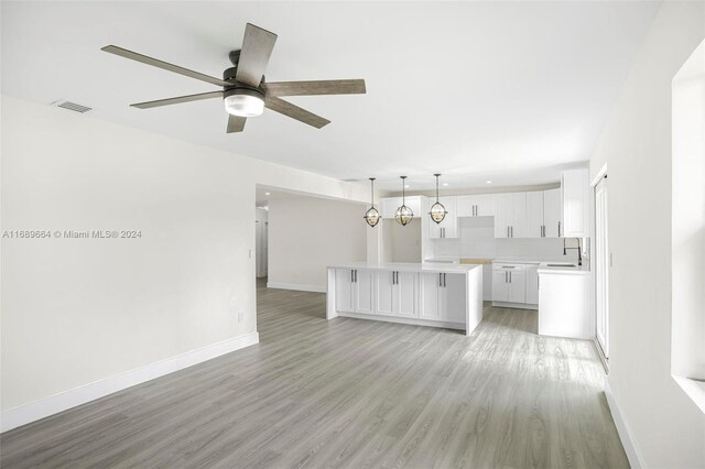 unfurnished living room with light hardwood / wood-style floors, sink, and ceiling fan