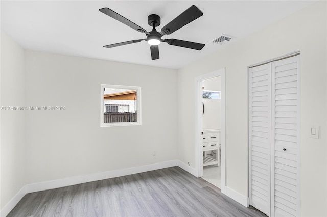 unfurnished bedroom with light hardwood / wood-style floors, ceiling fan, ensuite bath, and a closet