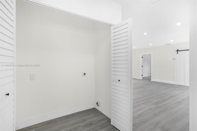 washroom with hookup for an electric dryer, hardwood / wood-style flooring, and a barn door