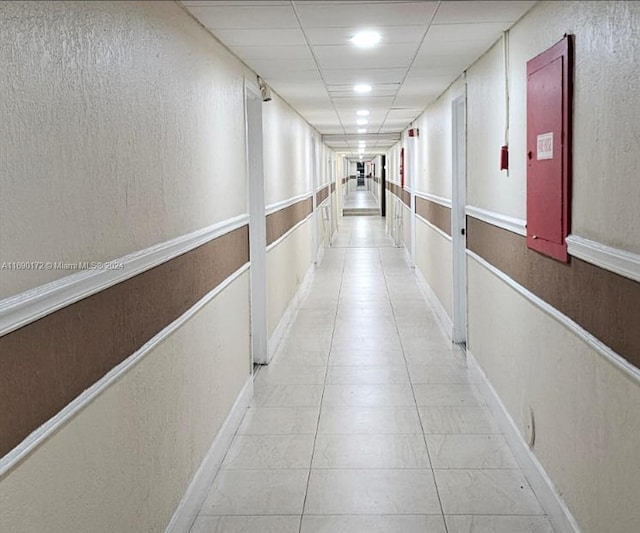 hall featuring a paneled ceiling and light tile patterned flooring