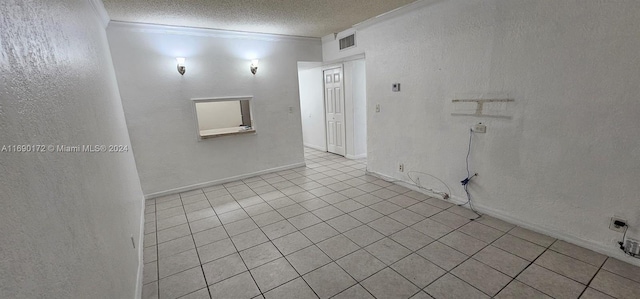 tiled empty room featuring a textured ceiling and ornamental molding