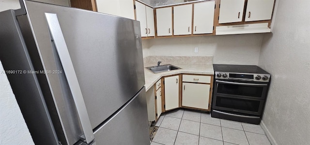 kitchen with white cabinets, appliances with stainless steel finishes, light tile patterned floors, and sink